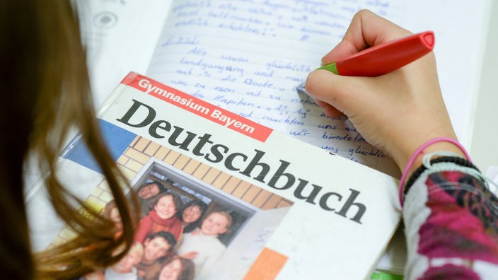 Ein Schulbuch für Deutschunterricht liegt auf dem Tisch einer Schülerin