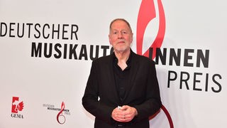 Dieter Gorny vor einer Wand mit der Aufschrift  "Deutscher Musikautore*innen Preis".