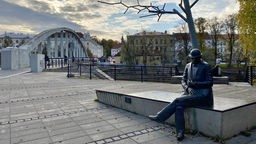 Tartu: Blick auf das Denkmal für den estnischen Journalisten und Dichter Johann Voldemar Jannsen mit der Bogenbrücke im Hintergrund.