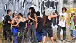 Aufnahme aus 2022: Junge Partygäste auf dem Gelände einer leerstehenden Fabrikhalle mit Graffitis.