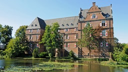 Blick auf das Wasserschloss Bedburg an einem sonnigen Tag.