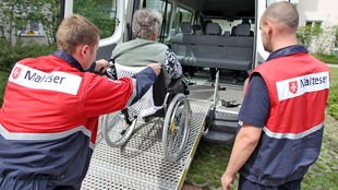 Zwei junge Männer helfen Rollstuhlfahrerin in ein Fahrzeug, Bundesfreiwilligendienst, Symbolbild, Archivbild: 24.08.2010
