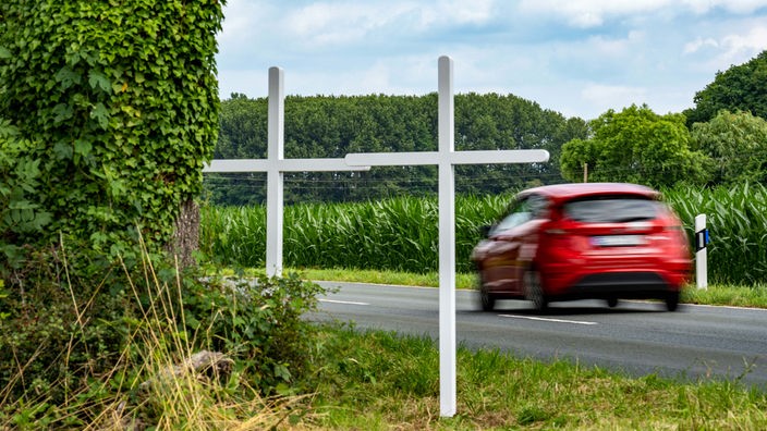 Zwei weiße Kreuze an einer Landstraße bei Kerken zum Gedenken an einen tödlichen Verkehrsunfall (2021).