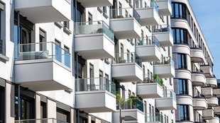 Die Fassade eines weißen modernen Wohnhauses mit vielen kleinen Balkonen.