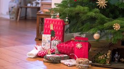 Unter einem geschmückten Weihnachtsbaum liegen Geschenke, Symbolbild