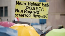 "Meine Heimat bleibt Deutsch" steht auf dem Schild eines Teilnehmers in Deutsch und Russisch bei einer Kundgebung der Bürgerinitiative "Sichere Heimat" am 14.02.2016 in Nürnberg.