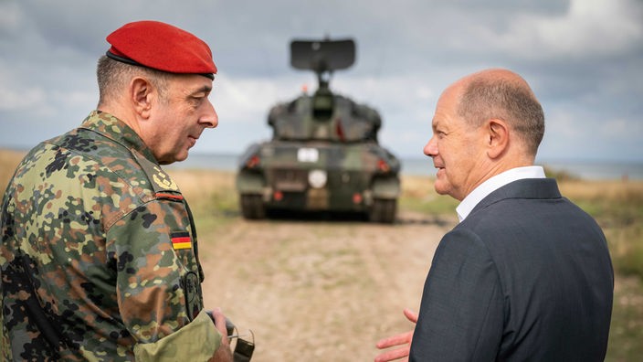 Bundeskanzler Olaf Scholz (SPD, r) spricht mit Generalmajor Carsten Breuer (l) über die Ausbildung ukrainischer Soldaten durch Krauss-Maffei Wegmann auf dem Truppenübungsplatz Putlos.