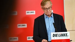 Dietmar Bartsch steht mit gesenktem Haupt an einem Redepult der Partei "Die Linke".