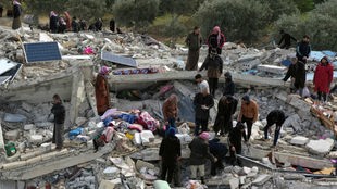 Zivilschutzmitarbeiter und Anwohner durchsuchen die Trümmer eingestürzter Gebäude nach Überlebenden, nachdem Erdbeben der Stärke 7,8 in Syrien und der Türkei Gebäude erschütterten. 