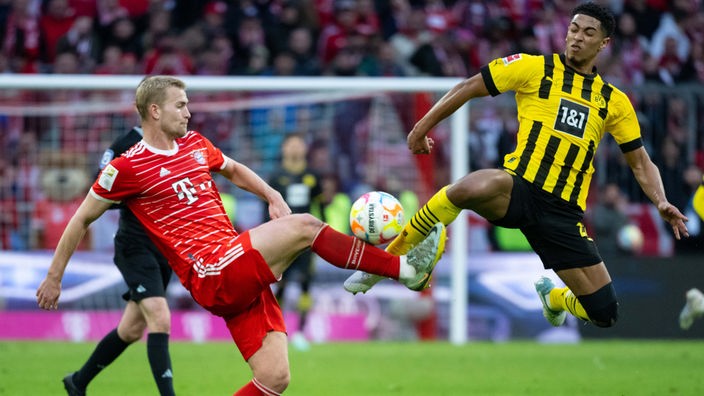 Bayern-Spieler Matthijs de Ligt (links) und Jude Bellingham von Borussia Dortmund kämpfen um den Ball. 