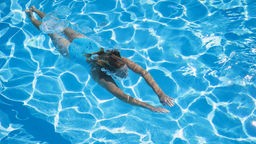 Eine Frau schwimmt in einem Pool: Schwimmen fördert die Gesundheit.