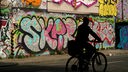 Ein Mann radelt an Graffiti im Londoner Stadtteil Tower Hamlets vorbei.