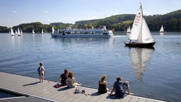 Junge Menschen sitzen auf einem Bootssteg in der Sonne und geniessen einen der letzten Sommertage des Jahres.