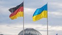 Die Ukrainische und Deutsche Flagge wehen in der Nähe des Bundestags nebeneinander.