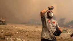 Waldbrände auf Rhodos: Ein freiwilliger Helfer kühlt sich während eines Waldbrandes in der Ortschaft Vati ab.