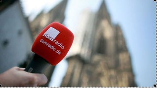 Mikrofon des Radiosenders ""Domradio" vor der Kulisse des Kölner Doms.