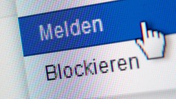 Hand zeigt auf einen blauen Balken mit Aufschrift "Melden", in der unteren Spalte des Bildes steht das Wort "Blockieren".  