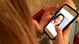Ein Teenager schaut auf einem Smartphone auf einen Werbefilm bei Instagram. 