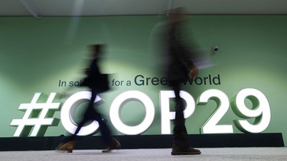 Während der COP29 laufen Menschen an einem COP29-Logo vorbei, Baku, Aserbaidschan, 14.11.2024.