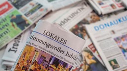 Lokalzeitung wird über andere Zeitungen gehalten. 