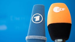 Die Mikrofone von ARD und ZDF sind vor einer Pressekonferenz nebeneinander aufgestellt. 
