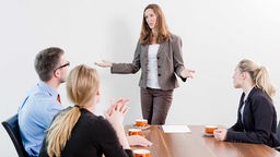 Eine Chefin leitet in einem Büro ein Meeting ihrer Mitarbeiter.