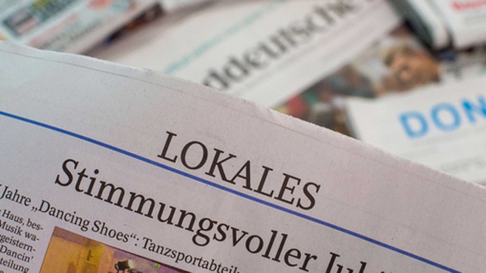 Eine Lokalzeitung wird über andere Zeitungen gehalten.