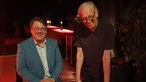 Helmut Schleich und Rainer Pause nach der Veranstaltung - stehend an einem roten Tisch.