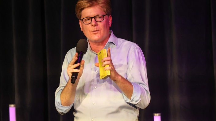 Herr Schröder mit Reclam Heft in der Hand auf der Bühne vom Theater am Dom