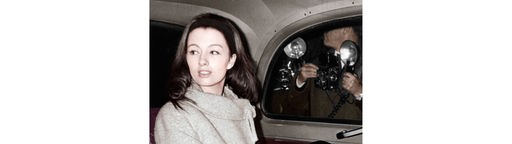 Eine Frau mit langen, schlanken Beinen sitzt auf der Rückbank eines Autos, draußen an der Scheibe sind Fotografen zu sehen, die sie ablichten, Aufnahme aus dem Jahr 1963 