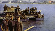 Deutsche Soldaten überqueren auf einer Ponton-Fähre einen Fluss