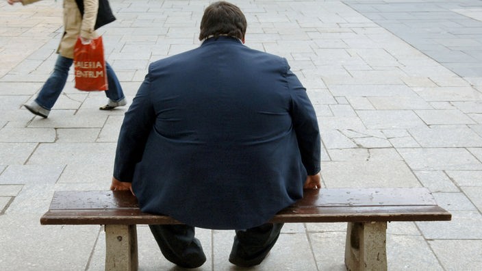 Übergewichtiger Mann sitzend auf einer Bank