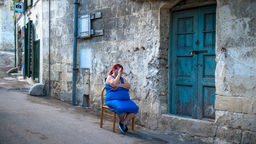 Eine Frau sitzt in Matera vor einem Haus. Die süditalienische Stadt Matera ist bekannt für ihre Höhlensiedlungen und war 2019 Europäische Kulturhauptstadt