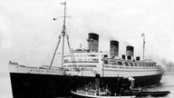 Der Luxusdampfer Queen Mary mit Bugsierschleppern längsseits um 1936