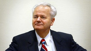 Ein Farbfoto zeigt Slobodan Milošević wird Staatspräsident von Jugoslawien, einen Mann mit Halbglatze, grauem Haar in dunklem Anzug, weißem Hemd und gestreifter Krawatte, sein Blick ist trotzig, selbstbewusst