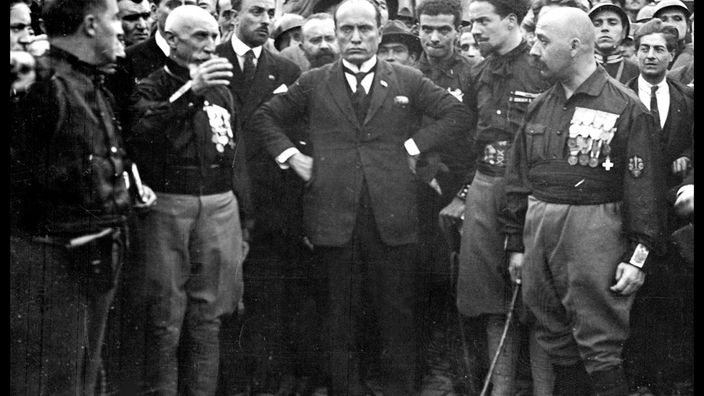 Benito Mussolini posiert 1922 mit verschränkten Armen inmitten seiner Anhänger