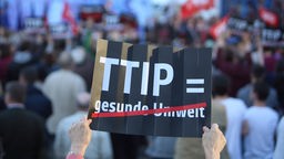 Schild mit Aufschrift TTIP gleich gesunde Umwelt, gesunde Umwelt ist durchgestrichen auf dem Schild