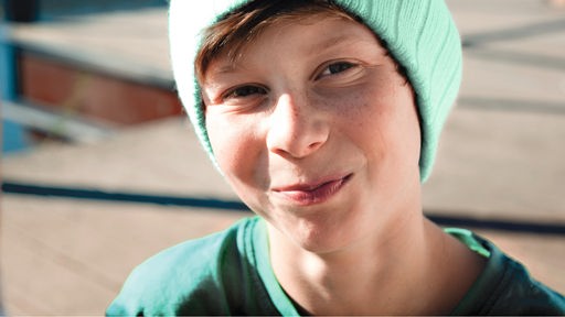 lächelnder Junge mit türkisfarbener Mütze