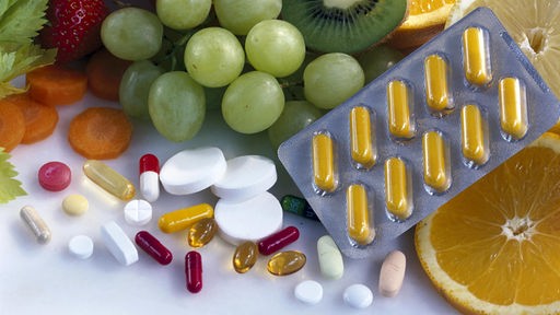 Vitamine in verschiedener Form: Als Tabletten und in Obst und Gemüse