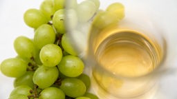 grüne Weintrauben und eine Glasflasche mit Essig