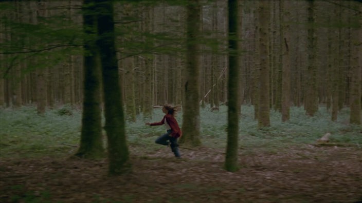 Ein Mädchen rennt durch den Wald.