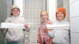 Die Schüler halten das Toilettenpapier in die Kamera