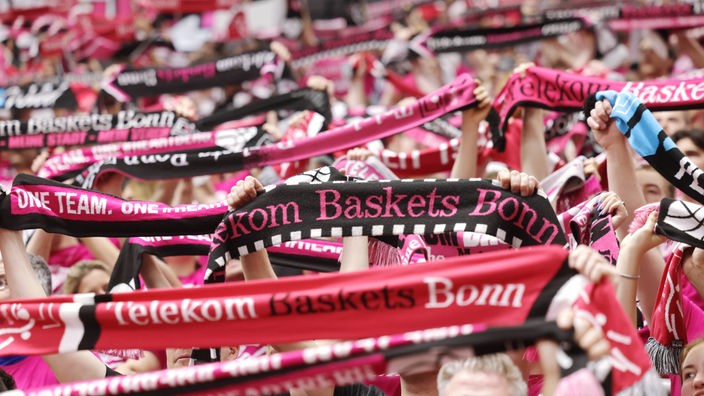 Fans der Telekom Baskets Bonn halten Schals in die Höhe