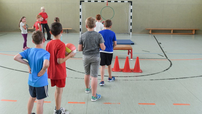 Kinder machen in einer Turnhalle Sport