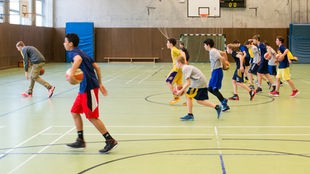 Kinder beim Basketballspielen in einer Turnhalle