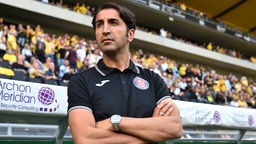 Hüzeyfe Dogan, Ex-Trainer des Wuppertaler SV, blickt an der Seitenlinie konzentriert drein.