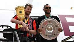 Jonathan Tah and Lukas Hradecky steigen mit dem DFB-Pokal und der Meisterschale aus dem Flieger am Flughafen in Köln