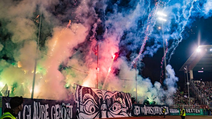 Anhänger von Preußen Münster brennen vor dem DFB-Pokalspiel gegen Bayern München ein Feuerwerk ab.