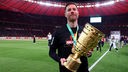 Trainer Xabi Alonso von Bayer 04 Leverkusen jubelt nach dem DFB-Pokalsieg im Olympiastadion mit der Trophäe