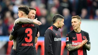 Bayer Leverkusens Meistertrainer Xabi Alonso (2.v.l.) umarmt Spieler Piero Hincapie